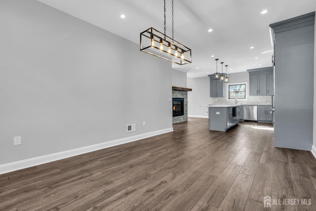 unfurnished living room with recessed lighting, a fireplace, visible vents, baseboards, and dark wood-style floors