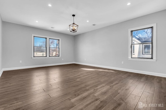 spare room with a notable chandelier, baseboards, dark wood-type flooring, and recessed lighting