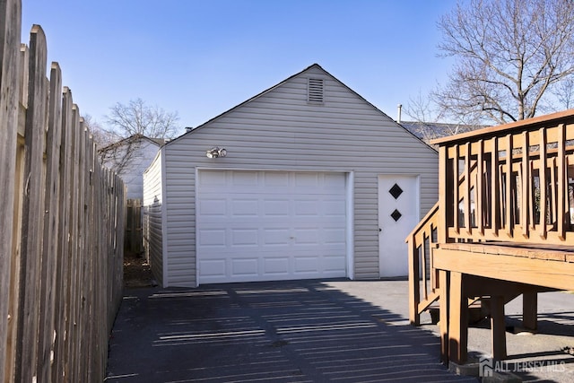 detached garage featuring fence and driveway