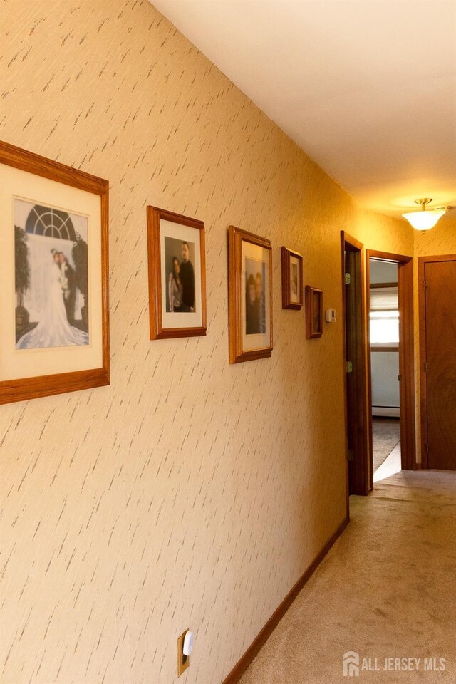 corridor featuring a baseboard radiator, baseboards, and carpet floors