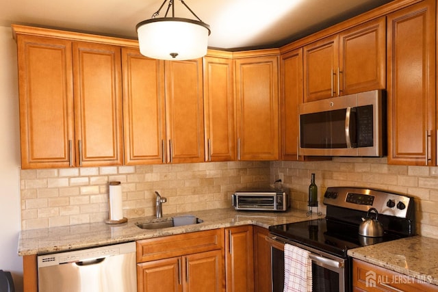 kitchen featuring appliances with stainless steel finishes, light stone counters, a sink, brown cabinets, and backsplash