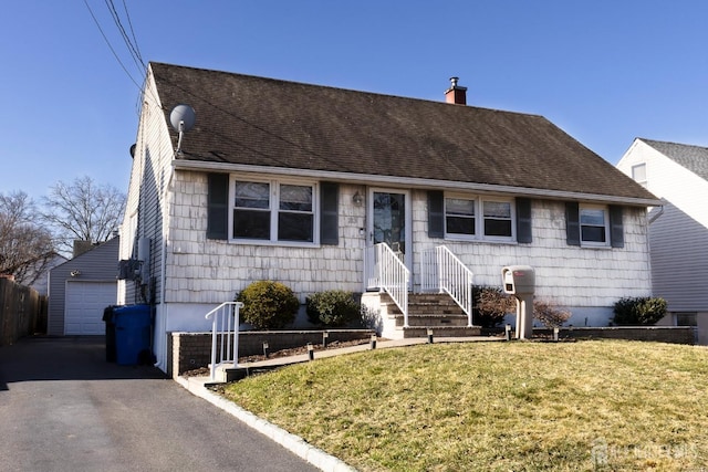 view of front of house with a front yard, a shingled roof, a garage, a chimney, and an outbuilding