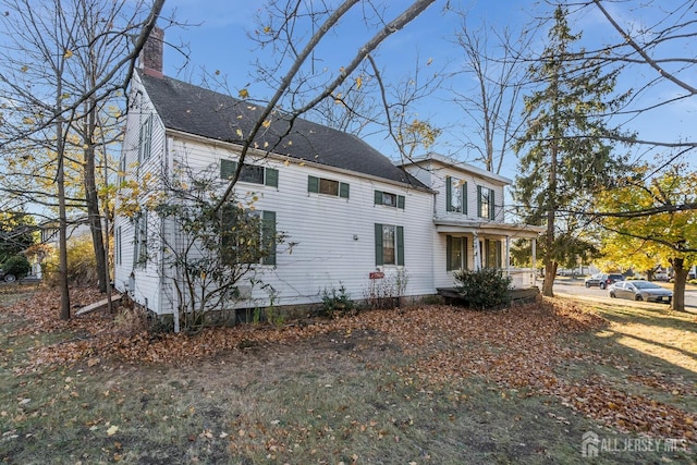 view of property exterior featuring roof with shingles, a porch, and a chimney