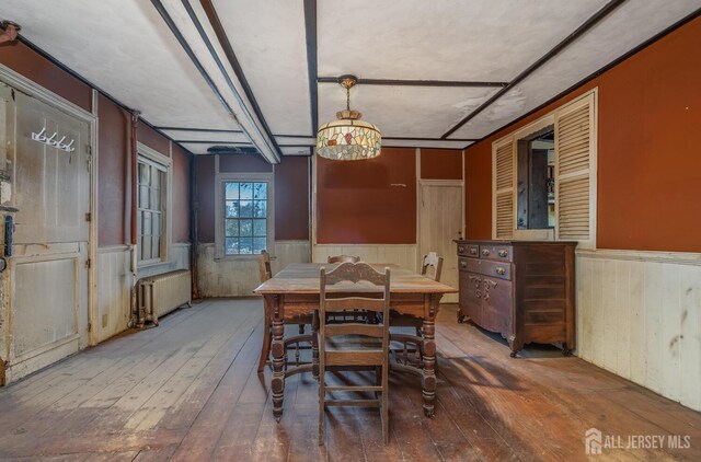 dining space featuring a notable chandelier, crown molding, hardwood / wood-style flooring, and radiator