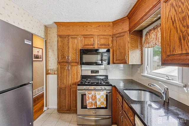 30 Clark Pl, Avenel, NJ 07001 - kitchen with appliances with stainless steel finishes, wallpapered walls, brown cabinets, a textured ceiling, and dark stone counters