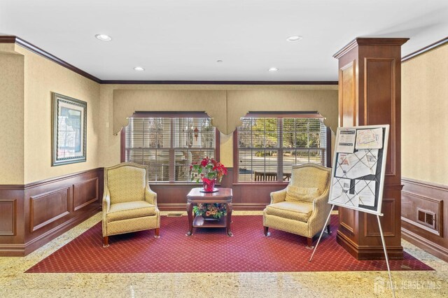 living area featuring ornamental molding and carpet flooring