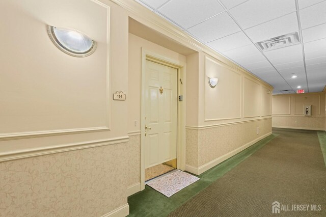 corridor featuring dark carpet and a drop ceiling