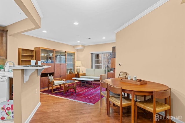 dining area featuring light hardwood / wood-style floors, sink, and ornamental molding