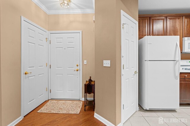 entrance foyer with crown molding and light hardwood / wood-style flooring