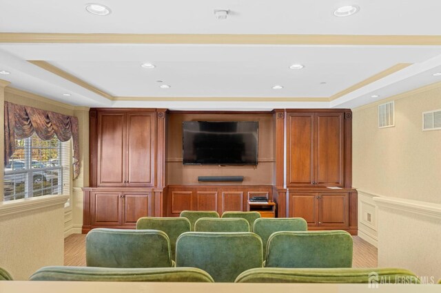 cinema featuring a raised ceiling and ornamental molding