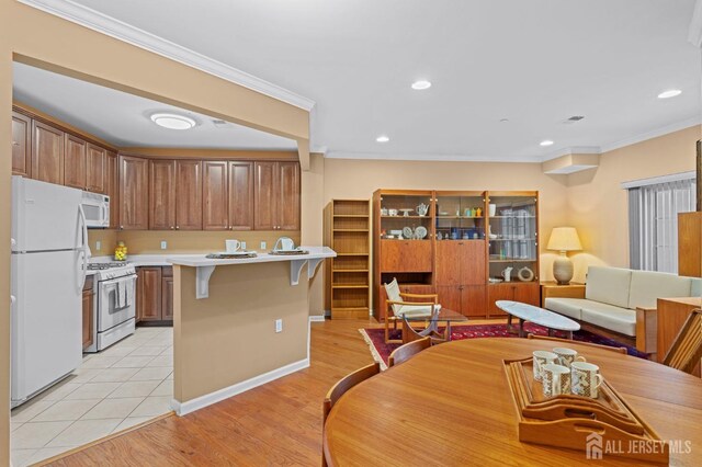 kitchen featuring white appliances, a center island, a kitchen bar, light tile patterned flooring, and crown molding