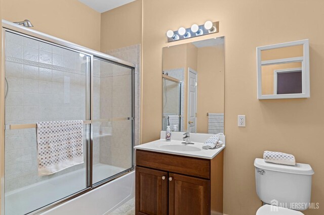 full bathroom with toilet, vanity, and shower / bath combination with glass door