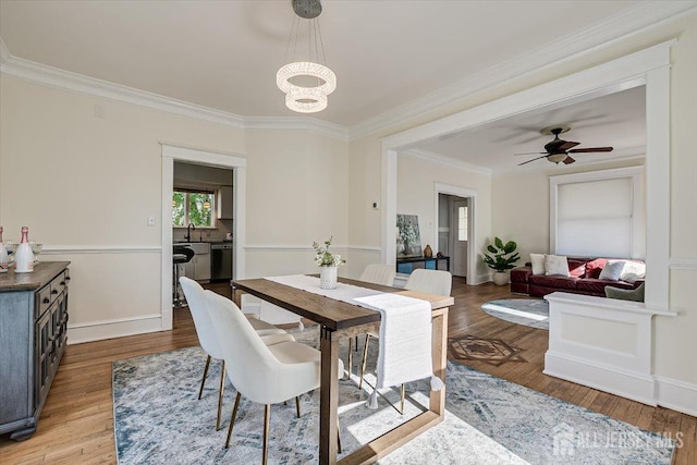 dining space with ceiling fan with notable chandelier, light wood-type flooring, ornamental molding, and sink