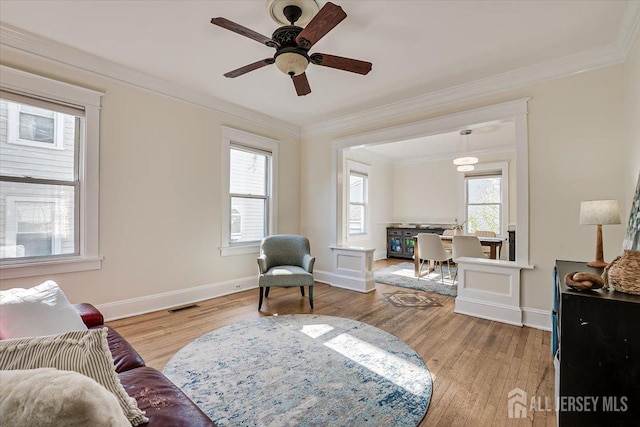 living area featuring plenty of natural light, crown molding, and light hardwood / wood-style flooring