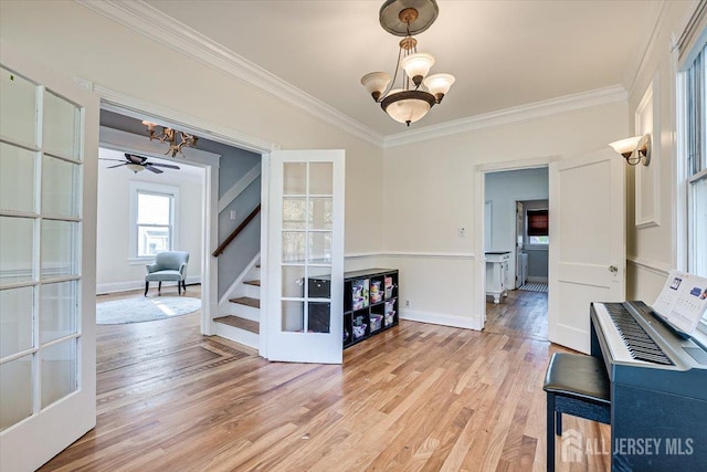 interior space featuring french doors, light wood-type flooring, crown molding, and a notable chandelier