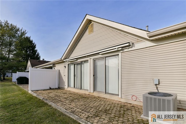 back of house with cooling unit and a lawn