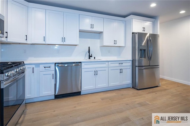 kitchen featuring white cabinets, sink, light wood-type flooring, and stainless steel appliances