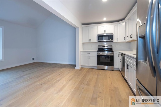 kitchen with decorative backsplash, white cabinetry, stainless steel appliances, and light hardwood / wood-style floors