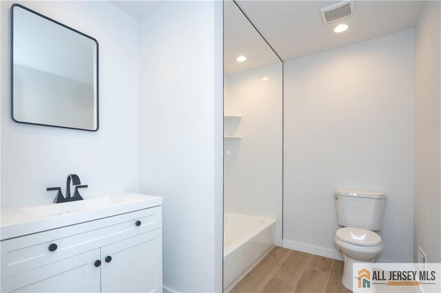 full bathroom with hardwood / wood-style floors, vanity, toilet, and bathtub / shower combination