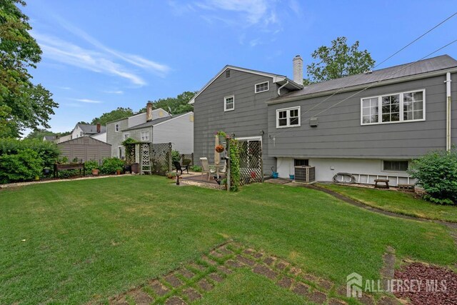 38 Foothills Dr, South River, NJ 08882 - rear view of house featuring cooling unit, a yard, and a chimney