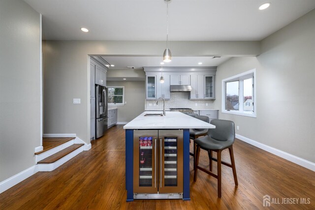 kitchen featuring sink, hanging light fixtures, beverage cooler, backsplash, and stainless steel fridge