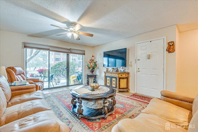 living room with ceiling fan and a textured ceiling