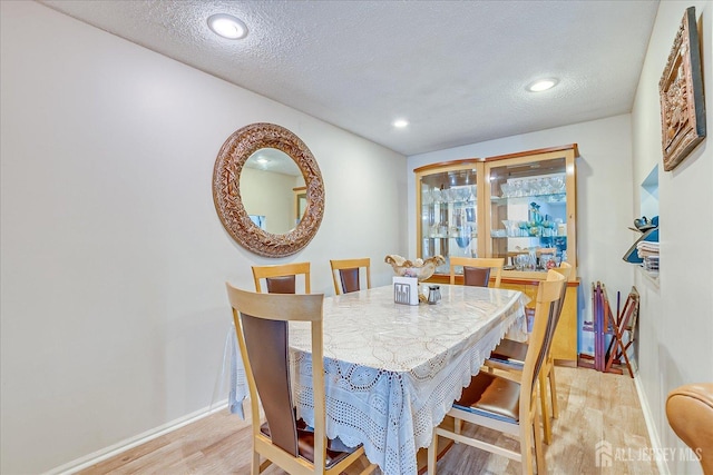 dining area featuring light wood-type flooring, a textured ceiling, baseboards, and recessed lighting