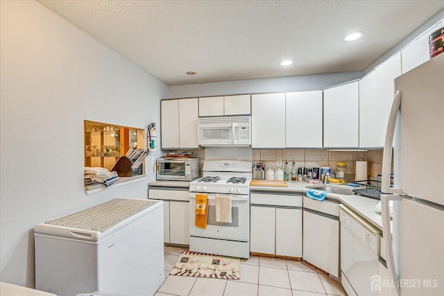 kitchen with white cabinets, white appliances, light countertops, and a sink