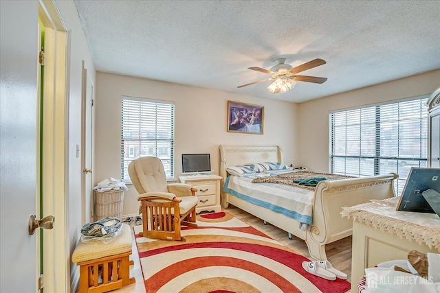 bedroom featuring light wood-style flooring, a ceiling fan, and a textured ceiling