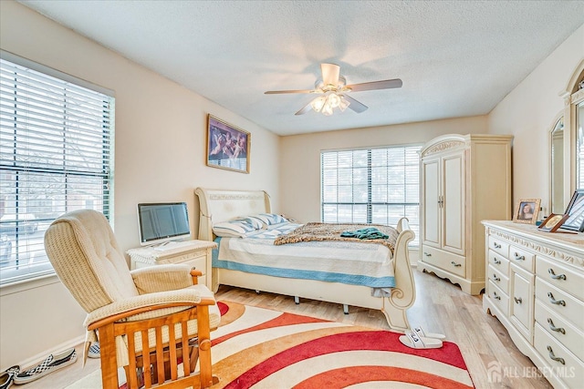 bedroom with light wood finished floors, ceiling fan, and a textured ceiling