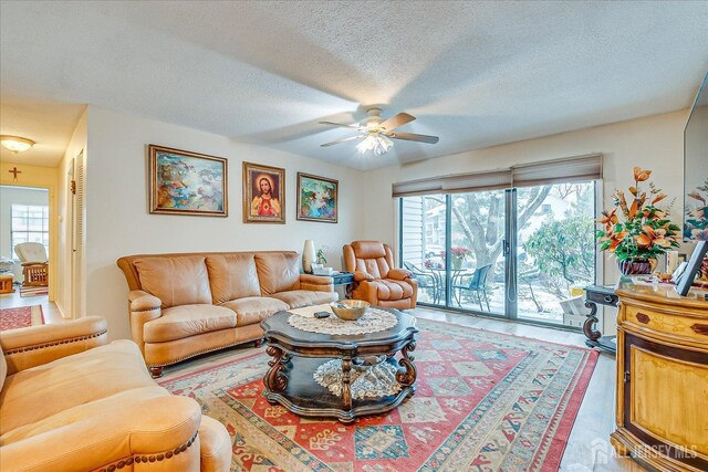 living room with ceiling fan and a textured ceiling