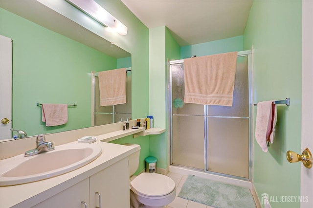 bathroom with a stall shower, vanity, toilet, and tile patterned floors