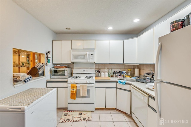 kitchen featuring light tile patterned floors, light countertops, backsplash, white cabinets, and white appliances