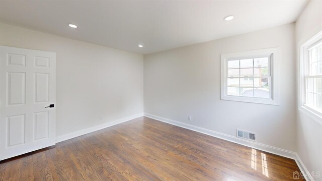 empty room featuring plenty of natural light and dark wood-type flooring