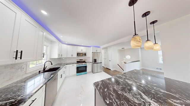 kitchen with decorative light fixtures, backsplash, stainless steel appliances, and white cabinetry