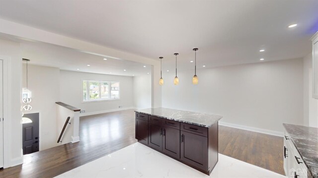 kitchen featuring light stone counters, white cabinets, hanging light fixtures, and a kitchen island