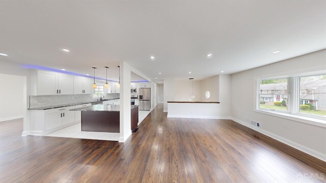 kitchen with pendant lighting, a center island, white cabinets, appliances with stainless steel finishes, and tasteful backsplash