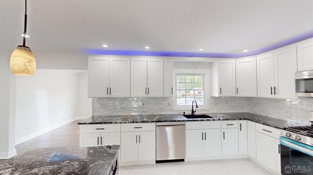 kitchen with white cabinetry, dark stone counters, decorative light fixtures, and appliances with stainless steel finishes