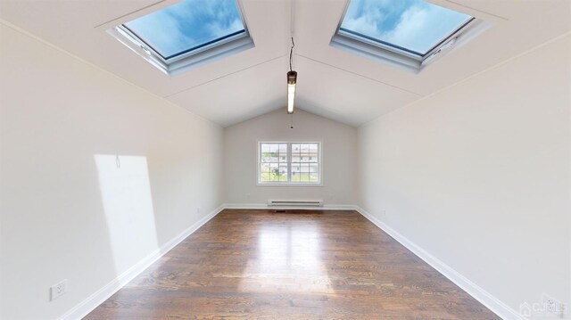 unfurnished room featuring vaulted ceiling with skylight, dark hardwood / wood-style flooring, and a baseboard heating unit