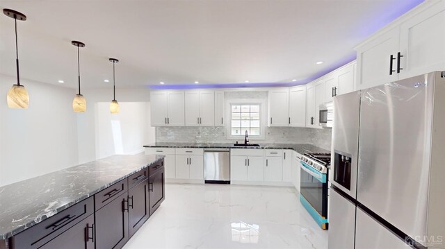 kitchen featuring white cabinetry, sink, hanging light fixtures, dark stone counters, and appliances with stainless steel finishes