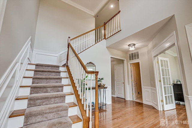 37 Equestrian Way, Monroe, NJ 08831 - stairs featuring wood finished floors, ornamental molding, a decorative wall, wainscoting, and a towering ceiling