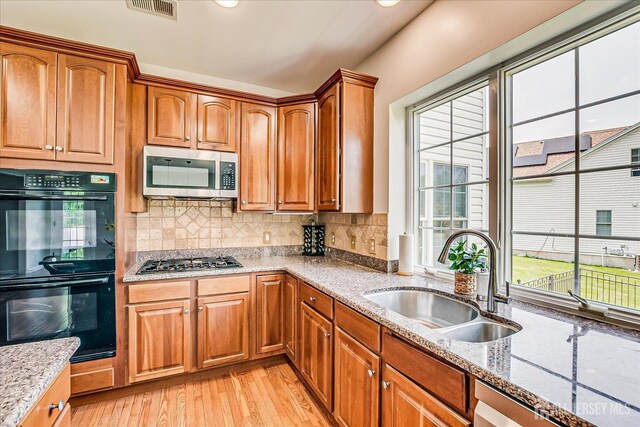 37 Equestrian Way, Monroe, NJ 08831 - kitchen featuring appliances with stainless steel finishes, a sink, light wood-type flooring, light stone countertops, and brown cabinetry