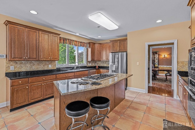 9 Narrow Brook Ct, Plainsboro, NJ 08536 - kitchen with a sink, brown cabinetry, a breakfast bar area, tasteful backsplash, and dark stone counters