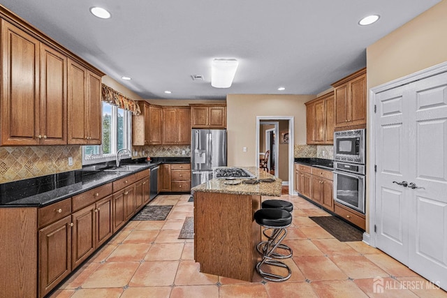 9 Narrow Brook Ct, Plainsboro, NJ 08536 - kitchen with stainless steel appliances, a sink, brown cabinetry, a breakfast bar area, and dark stone countertops