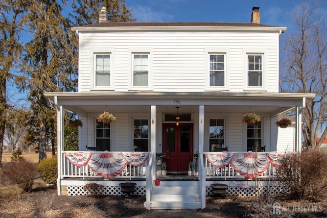 view of front facade with covered porch and a chimney