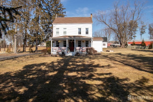 rear view of house with covered porch and a yard