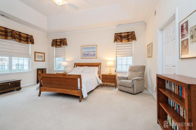 carpeted bedroom with a tray ceiling, ornamental molding, and ceiling fan