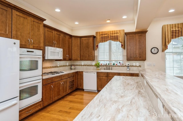 kitchen with sink, a healthy amount of sunlight, white appliances, and light hardwood / wood-style floors