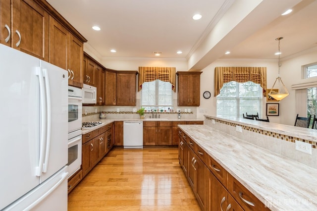 kitchen with light hardwood / wood-style floors, sink, white appliances, tasteful backsplash, and pendant lighting