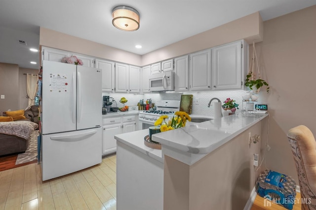 82 Heather Ct, South Brunswick, NJ 08852 - kitchen with white appliances, a peninsula, backsplash, white cabinets, and a sink